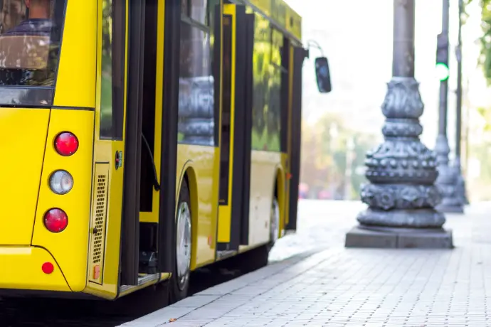 Yellow public bus parked at station in urban environment