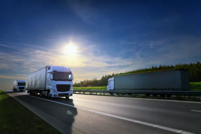 Freight truck driving on highway at sunrise, symbolizing long-haul logistics