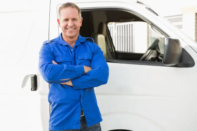 Smiling field technician in blue shirt standing in front of a service van