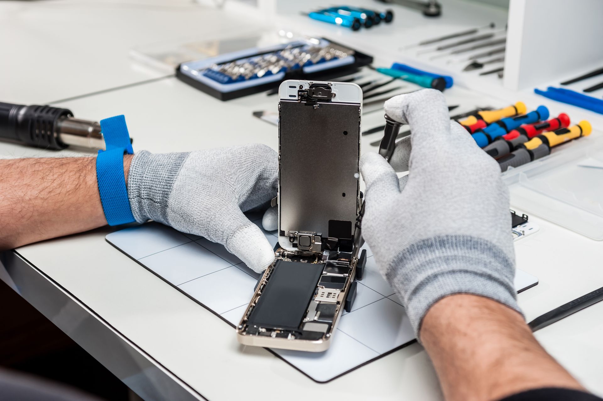 Réparations locales certifiées par eutronix garantissant rapidité, fiabilité et pièces d’origine Technicien ganté réparant un appareil mobile avec des outils spécialisés