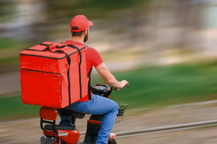 Cyclist with red backpack riding for food delivery, equipped with rugged mobile mount